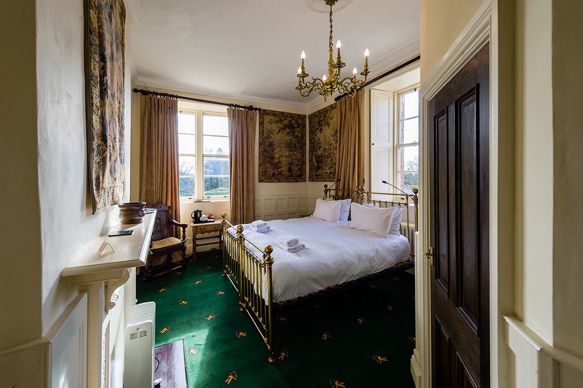 Large brass bed and decorative wall coverings in the Hothfield bedroom at Appleby Castle