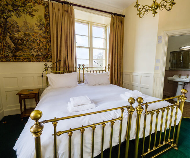 Large brass bed and decorative wall coverings in the Hothfield bedroom at Appleby Castle