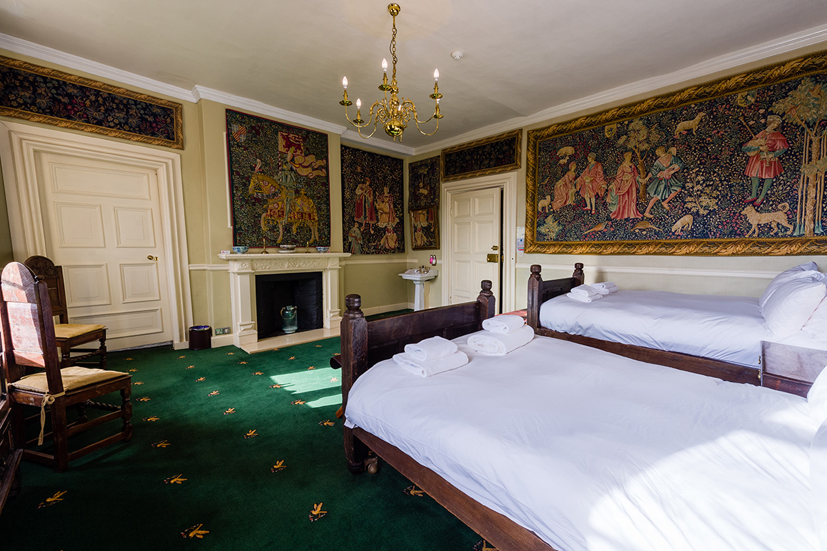 Decorative wall coverings and antique twin beds in the Tufton bedroom at Appleby Castle