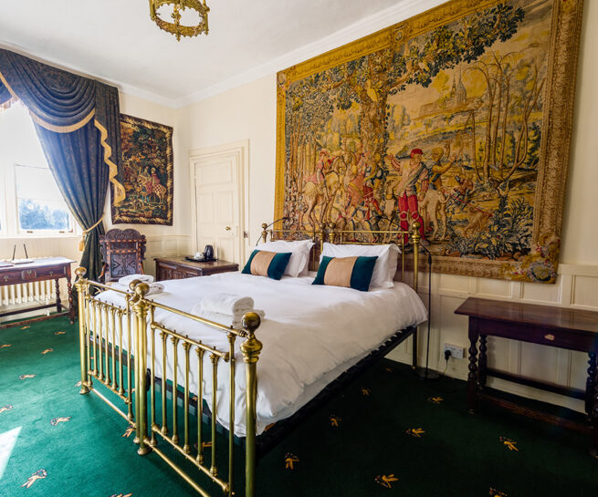 Large brass bed and decorative wall coverings in the Thanet bedroom at Appleby Castle