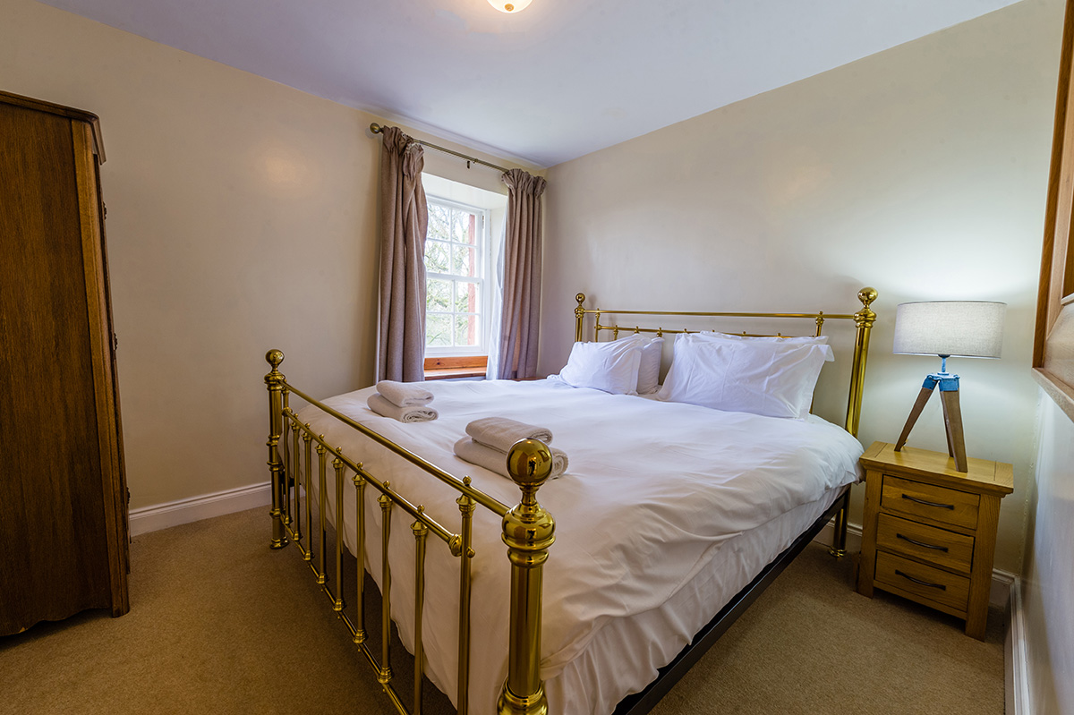 Large brass bed in the self-contained holiday cottage at Appleby Castle in Cumbria